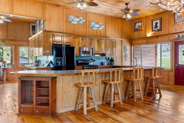 kitchen featuring black fridge with ice dispenser, light wood-type flooring, gas stove, and wood ceiling