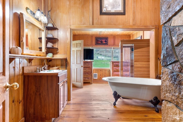 bathroom featuring wooden walls, vanity, a bathing tub, and hardwood / wood-style floors