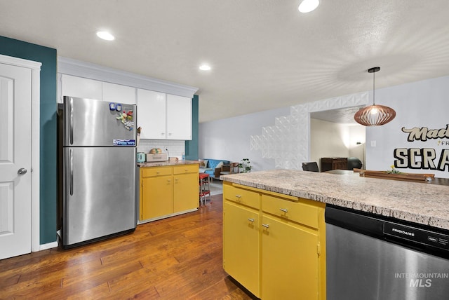 kitchen with dark hardwood / wood-style flooring, backsplash, stainless steel appliances, pendant lighting, and white cabinetry