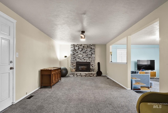 living room featuring carpet flooring, a textured ceiling, and a stone fireplace