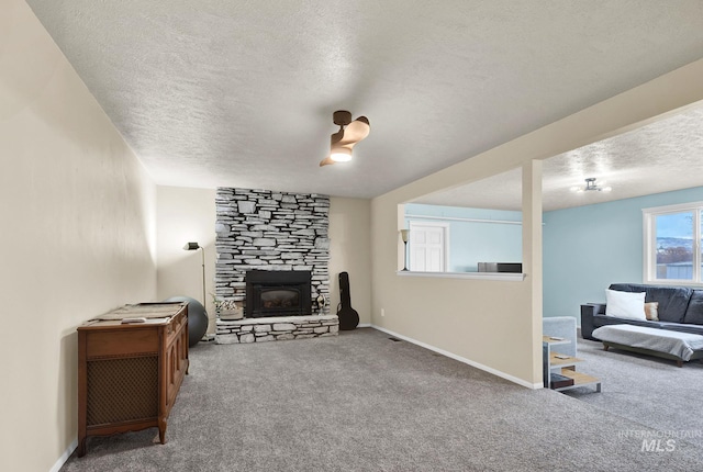 living room with a stone fireplace, carpet floors, and a textured ceiling