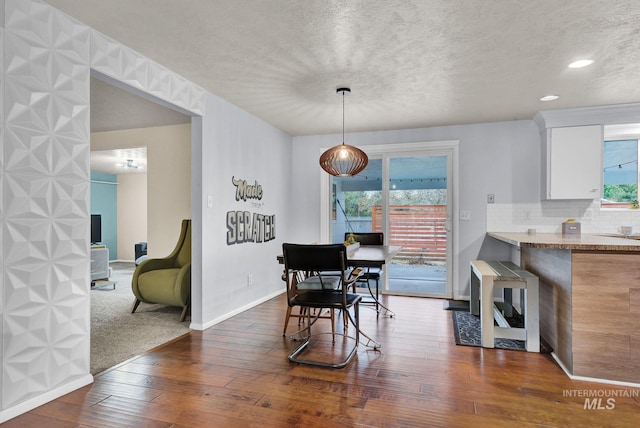 dining space with a textured ceiling, dark hardwood / wood-style flooring, and a wealth of natural light