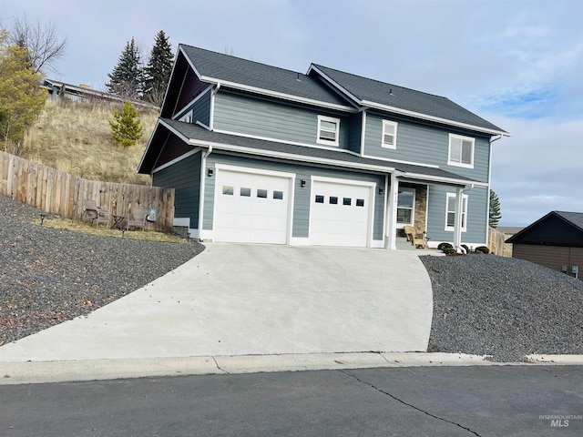 traditional-style home featuring a garage, concrete driveway, and fence