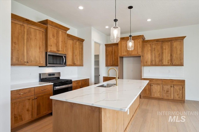 5351 W Mcnair St, Meridian, ID 83646 - kitchen featuring appliances with stainless steel finishes, a sink, brown cabinetry, tasteful backsplash, and light wood finished floors