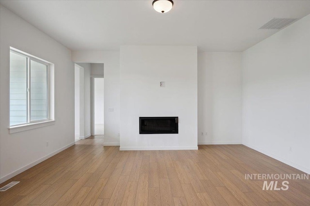 5351 W Mcnair St, Meridian, ID 83646 - unfurnished living room featuring light wood finished floors, a glass covered fireplace, and baseboards