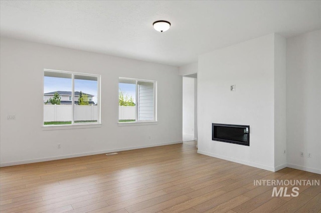 5351 W Mcnair St, Meridian, ID 83646 - unfurnished living room featuring a glass covered fireplace, light wood-type flooring, and baseboards