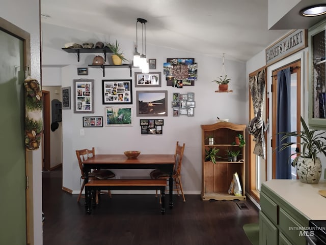 dining room featuring lofted ceiling, dark wood-type flooring, and baseboards