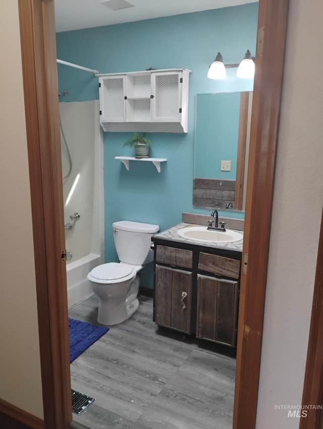 bathroom with vanity,  shower combination, toilet, and wood finished floors