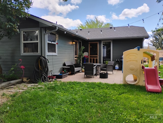 rear view of property featuring a patio area, a lawn, and roof with shingles