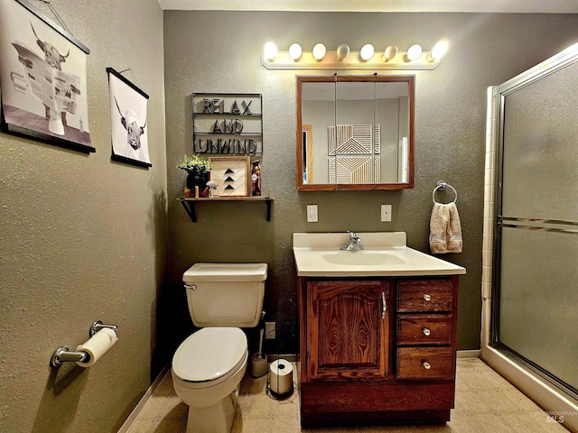 full bath featuring toilet, baseboards, vanity, and a shower with shower door