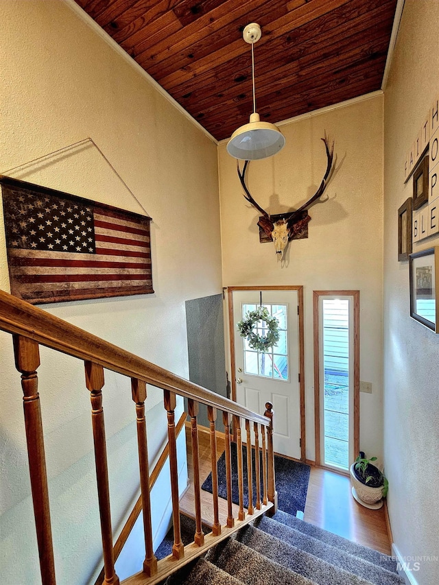 foyer entrance with crown molding, wood ceiling, stairway, and a textured wall