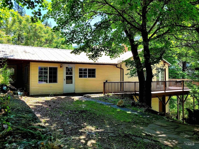 back of house with metal roof and a wooden deck