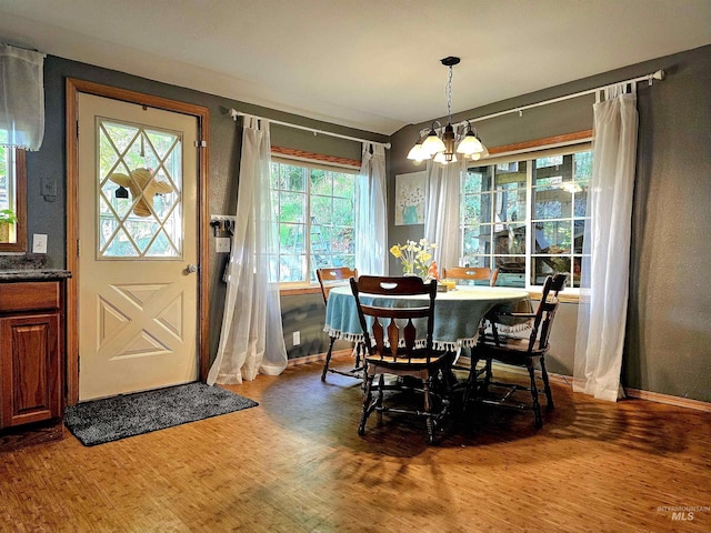dining room with baseboards, a wealth of natural light, a chandelier, and wood finished floors