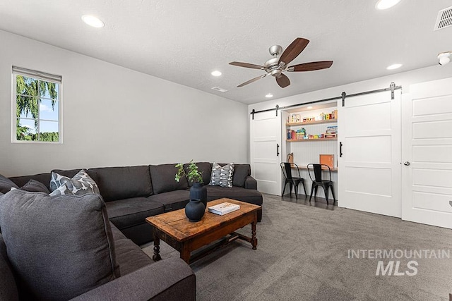 carpeted living area with recessed lighting, a barn door, ceiling fan, and visible vents