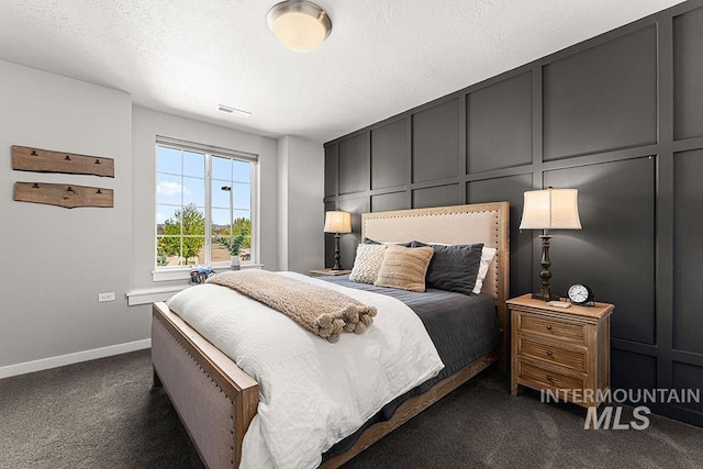 bedroom featuring dark carpet, baseboards, a decorative wall, and visible vents