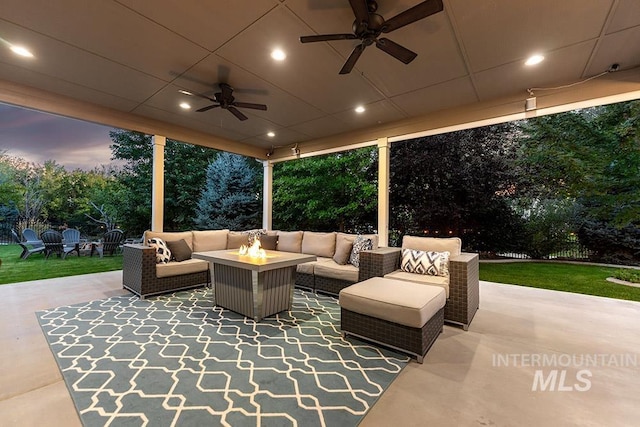 view of patio / terrace with ceiling fan and an outdoor living space with a fire pit