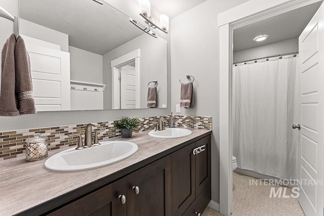 full bathroom with double vanity, a sink, backsplash, and toilet