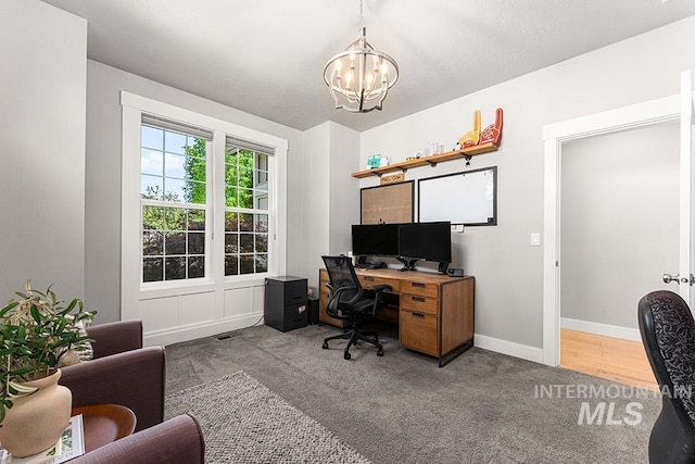 carpeted home office featuring an inviting chandelier, baseboards, and visible vents