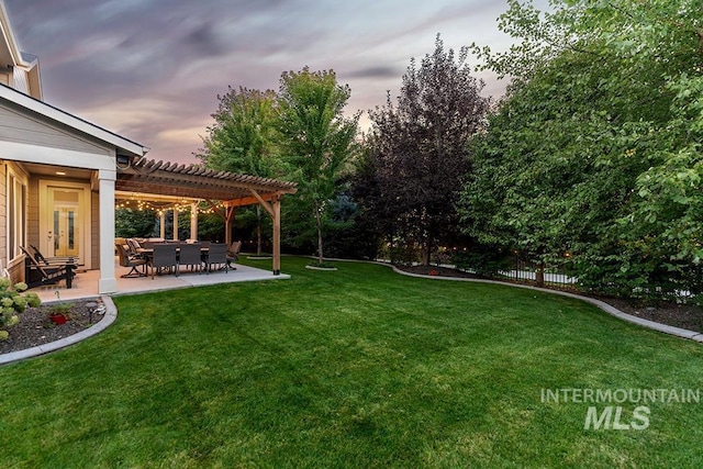 yard at dusk with fence, a pergola, and a patio