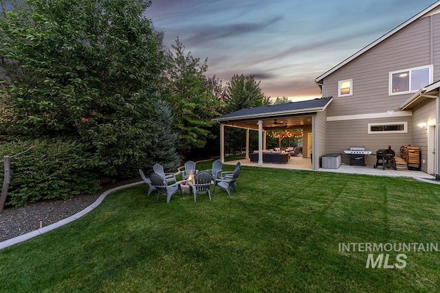 view of yard with a patio, a ceiling fan, and an outdoor living space with a fire pit