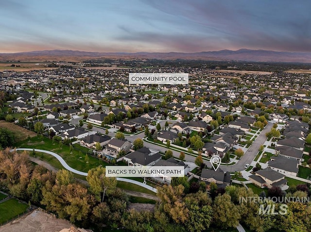 aerial view at dusk featuring a mountain view and a residential view