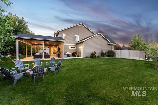rear view of house featuring a lawn, a patio, a ceiling fan, and an outdoor living space with a fire pit