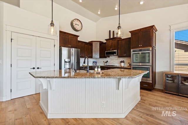 kitchen featuring stainless steel appliances, light stone countertops, and light wood finished floors