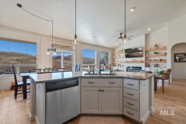 kitchen with light stone counters, a fireplace, a sink, a textured ceiling, and dishwasher