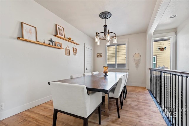 dining room with light wood-style flooring, baseboards, and an inviting chandelier