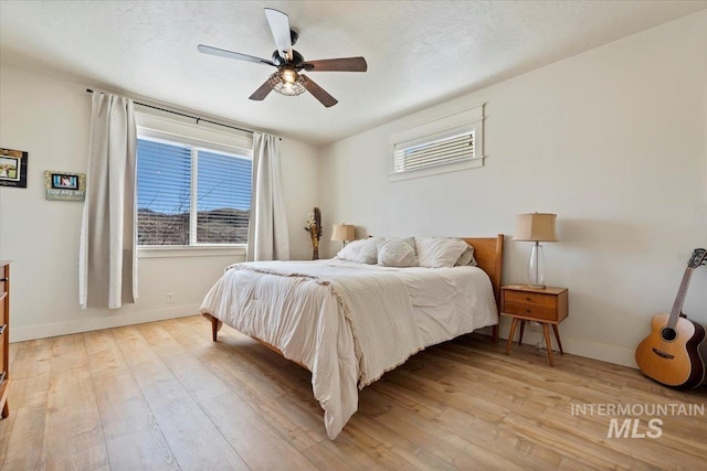 bedroom featuring baseboards, a textured ceiling, and light wood-style flooring