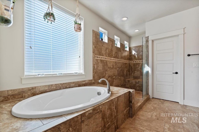 full bathroom featuring plenty of natural light, a garden tub, and a tile shower