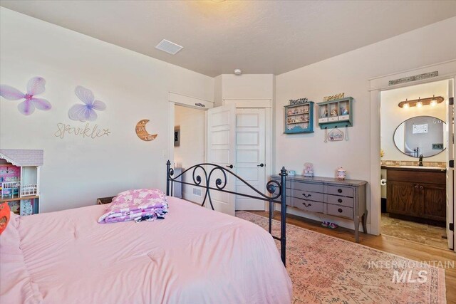 bedroom featuring visible vents, ensuite bath, and light wood-type flooring