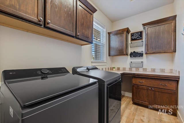 laundry area with cabinet space, light wood-style floors, and washing machine and clothes dryer