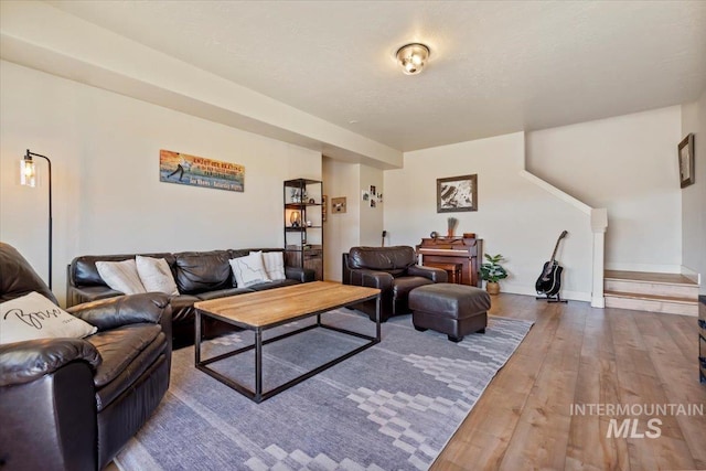 living area with baseboards, wood-type flooring, and a textured ceiling