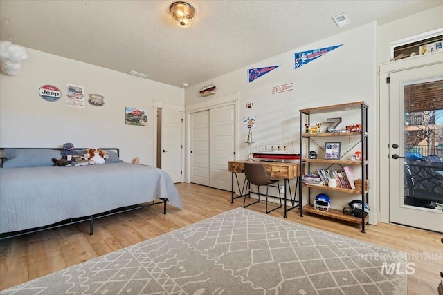 bedroom featuring visible vents, a textured ceiling, and wood finished floors