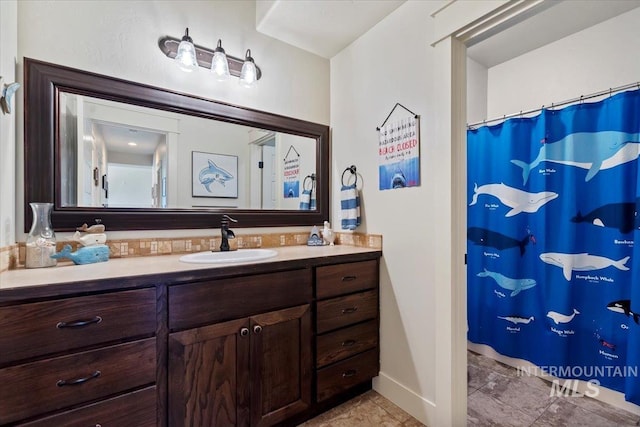 full bath featuring curtained shower, baseboards, and vanity