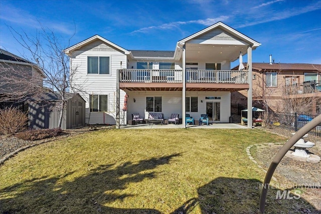 back of property featuring a patio, fence, a yard, an outdoor structure, and a storage shed