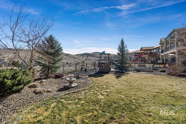 view of yard with a mountain view, a playground, and fence