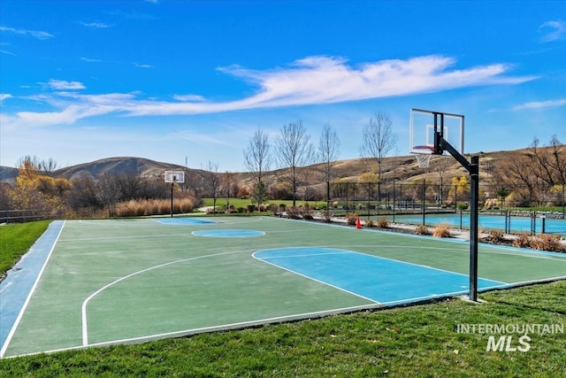 view of basketball court featuring community basketball court, a mountain view, and fence