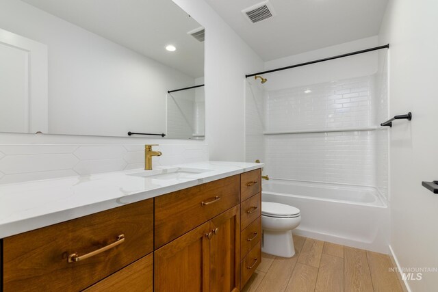 12510 W Wild Thistle Dr, Star, ID 83669 - full bathroom with vanity, backsplash, toilet, wood finished floors, and tub / shower combination