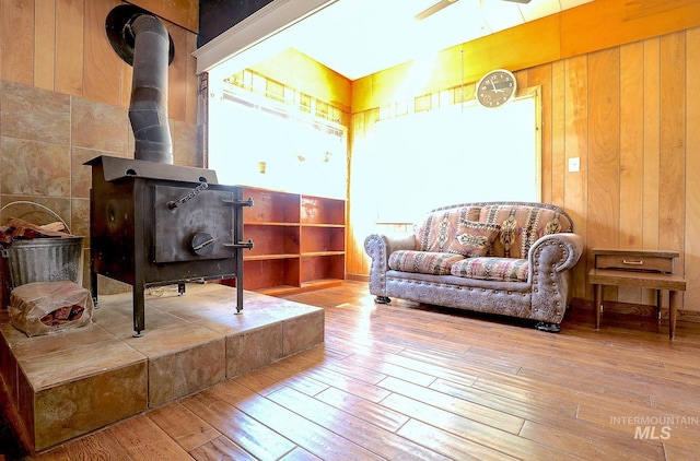 sitting room featuring a wood stove, wood walls, and light wood-style flooring