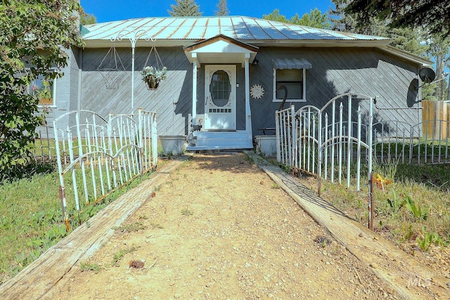 view of front facade featuring entry steps, metal roof, and fence