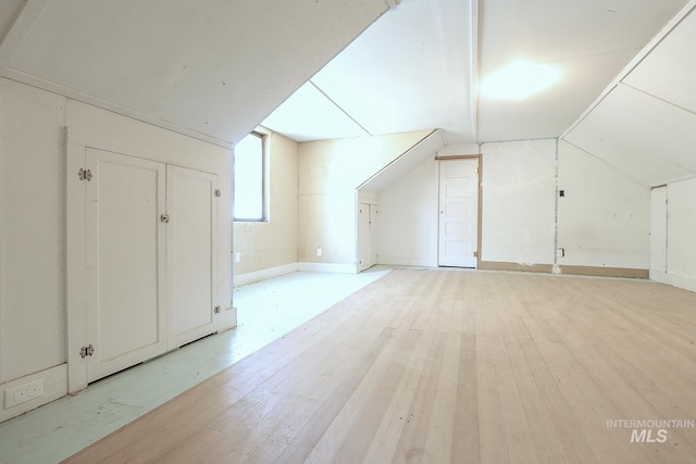 additional living space with light wood-type flooring and vaulted ceiling