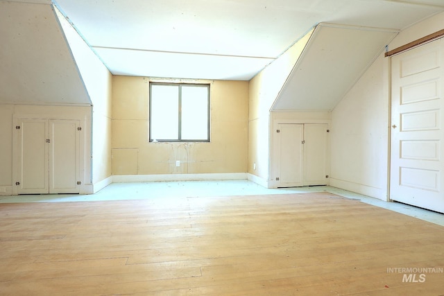 bonus room with lofted ceiling, light wood-style flooring, and baseboards