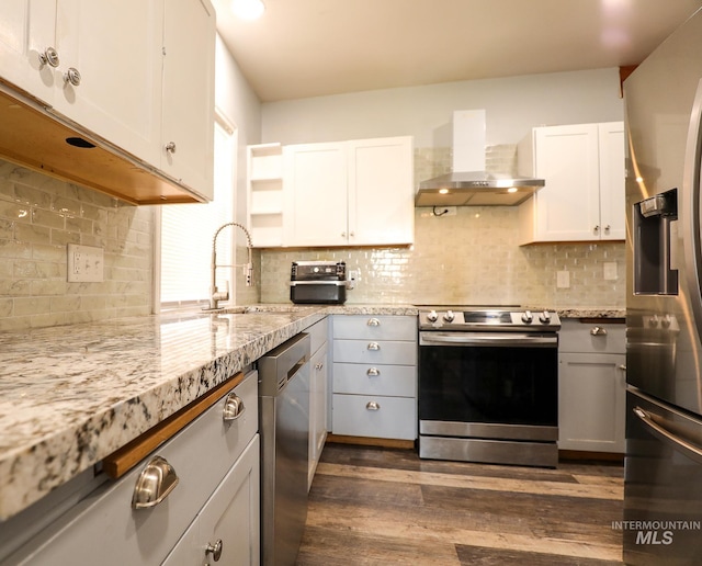 kitchen with appliances with stainless steel finishes, white cabinetry, wall chimney range hood, and open shelves