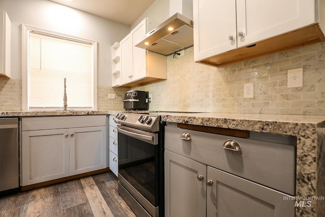 kitchen featuring wall chimney exhaust hood, appliances with stainless steel finishes, white cabinetry, open shelves, and a sink