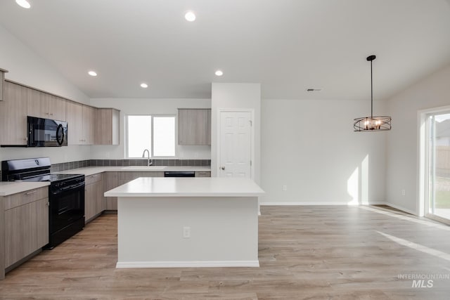 kitchen with a center island, lofted ceiling, a sink, modern cabinets, and black appliances