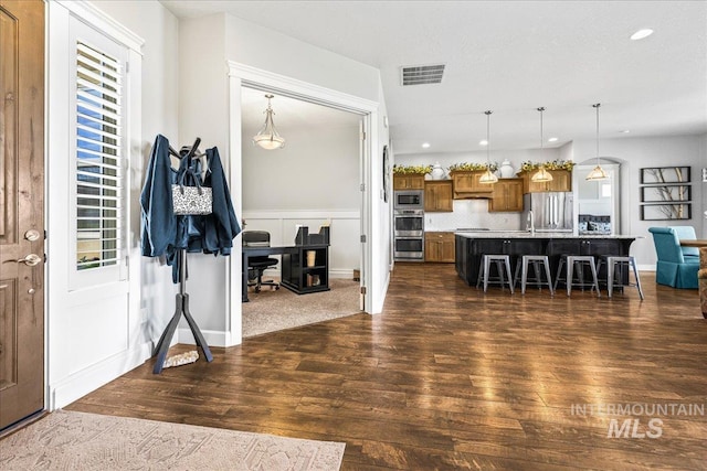 9968 Moon Shadow Ct, Middleton, ID 83644 - kitchen featuring brown cabinets, appliances with stainless steel finishes, a kitchen bar, dark wood-style flooring, and recessed lighting