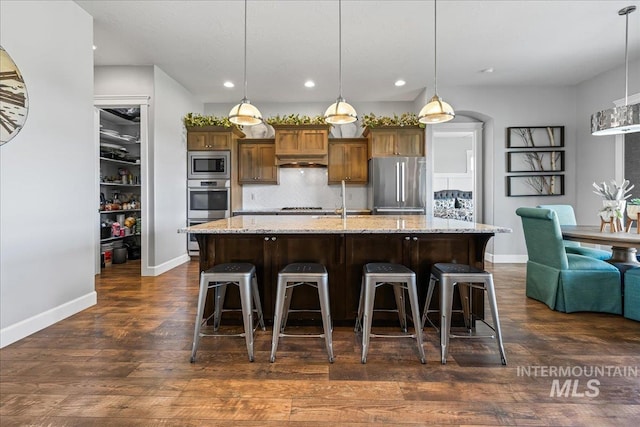 9968 Moon Shadow Ct, Middleton, ID 83644 - kitchen featuring appliances with stainless steel finishes, recessed lighting, decorative backsplash, a breakfast bar area, and dark wood-type flooring