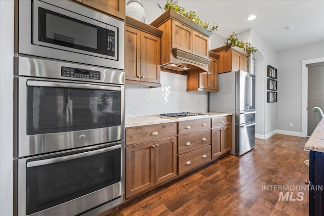 9968 Moon Shadow Ct, Middleton, ID 83644 - kitchen with stainless steel appliances, dark wood-style flooring, backsplash, light stone counters, and brown cabinets
